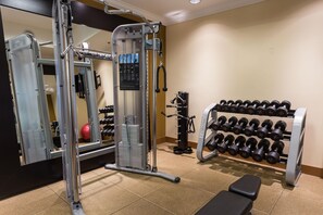 A gym with weightlifting equipment, a bench, and a rack of dumbbells. - Hilton Garden Inn San Mateo (San Mateo)