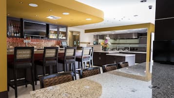 A modern kitchen with a bar area, granite countertops, and a dining space with bar stools.