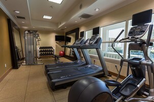 A gym with treadmills, a weight bench, and a wall-mounted TV.