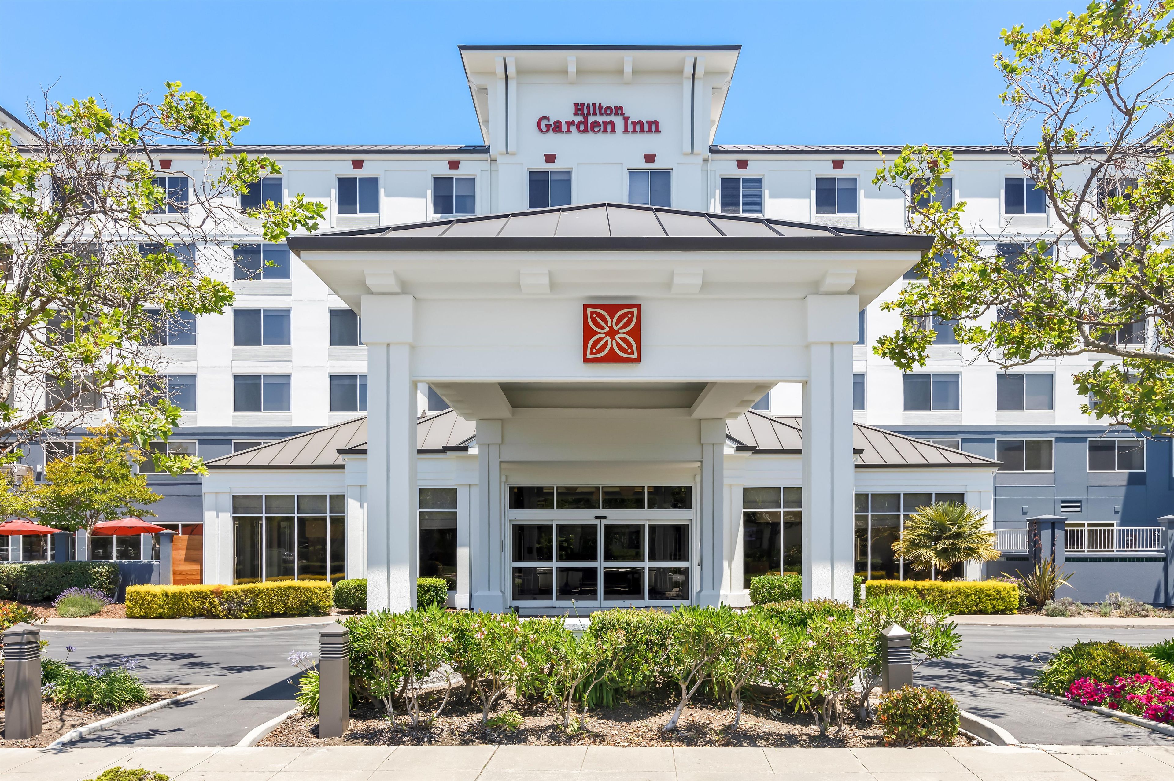A Hilton Garden Inn with a central entrance, multiple windows, and a clear sky.