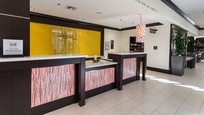 A hotel reception area with a modern design, featuring a reception desk, a yellow accent wall, and a ceiling with a motivational quote. - Hilton Garden Inn San Mateo (San Mateo)