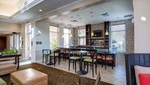 A spacious lobby with a bar area, seating, and a patterned carpet.