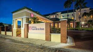 A Hilton Garden Inn with a brick facade, a signboard, and a gated entrance.