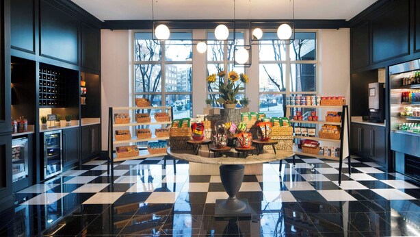 A modern interior with a central display of snacks and beverages, large windows, and a checkered floor.