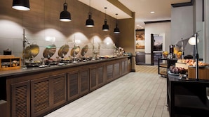 A buffet area with multiple food stations, overhead lighting, and a clean, modern design.