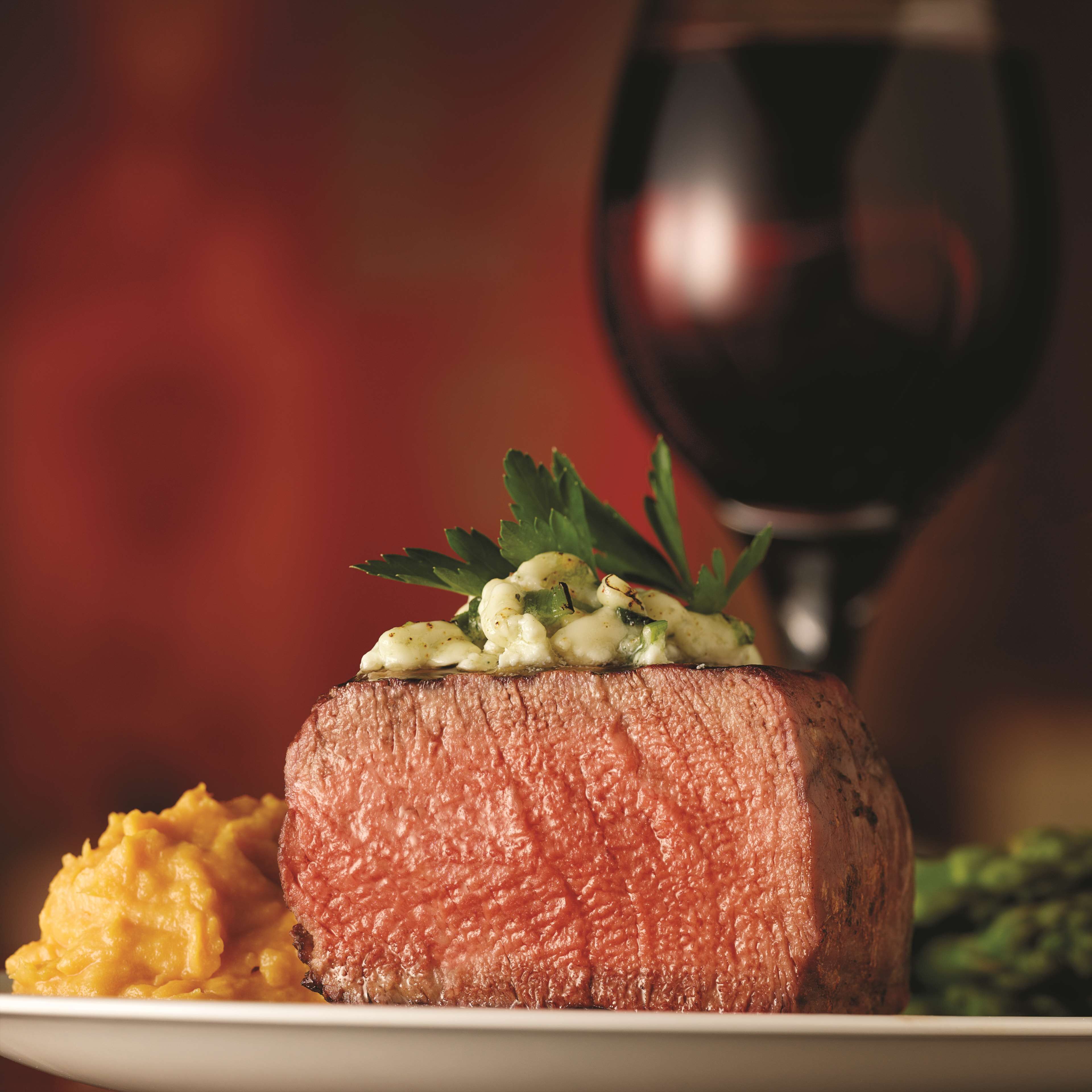 A steak with a garnish of herbs and a side of mashed potatoes.