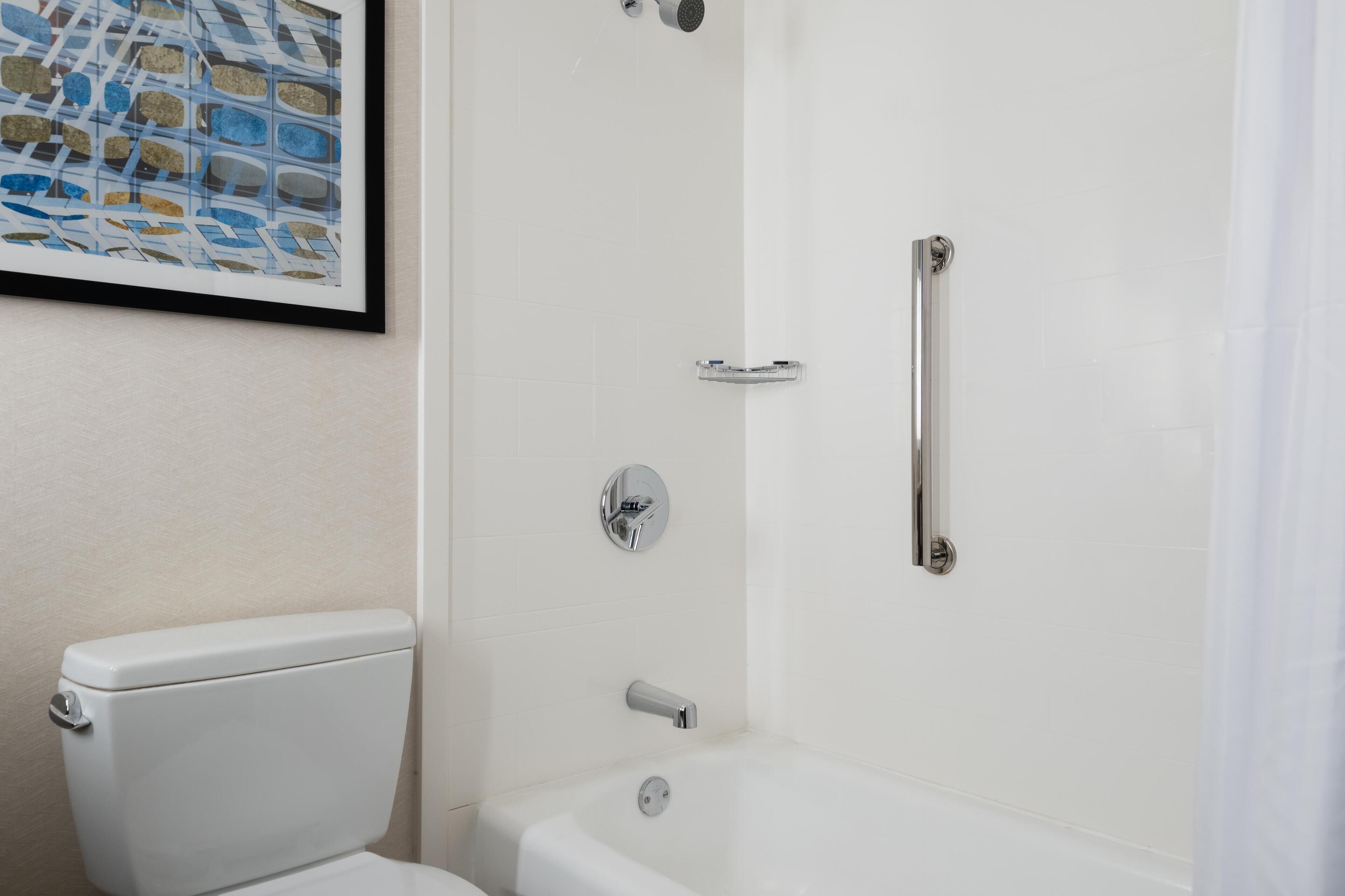 Een badkamer met een toilet, een douche met een glazen deur en een lijstwerk met kunst aan de muur.