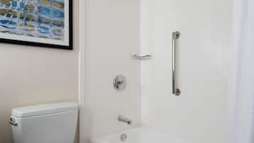 A bathroom with a toilet, a shower with a glass door, and a framed artwork on the wall.