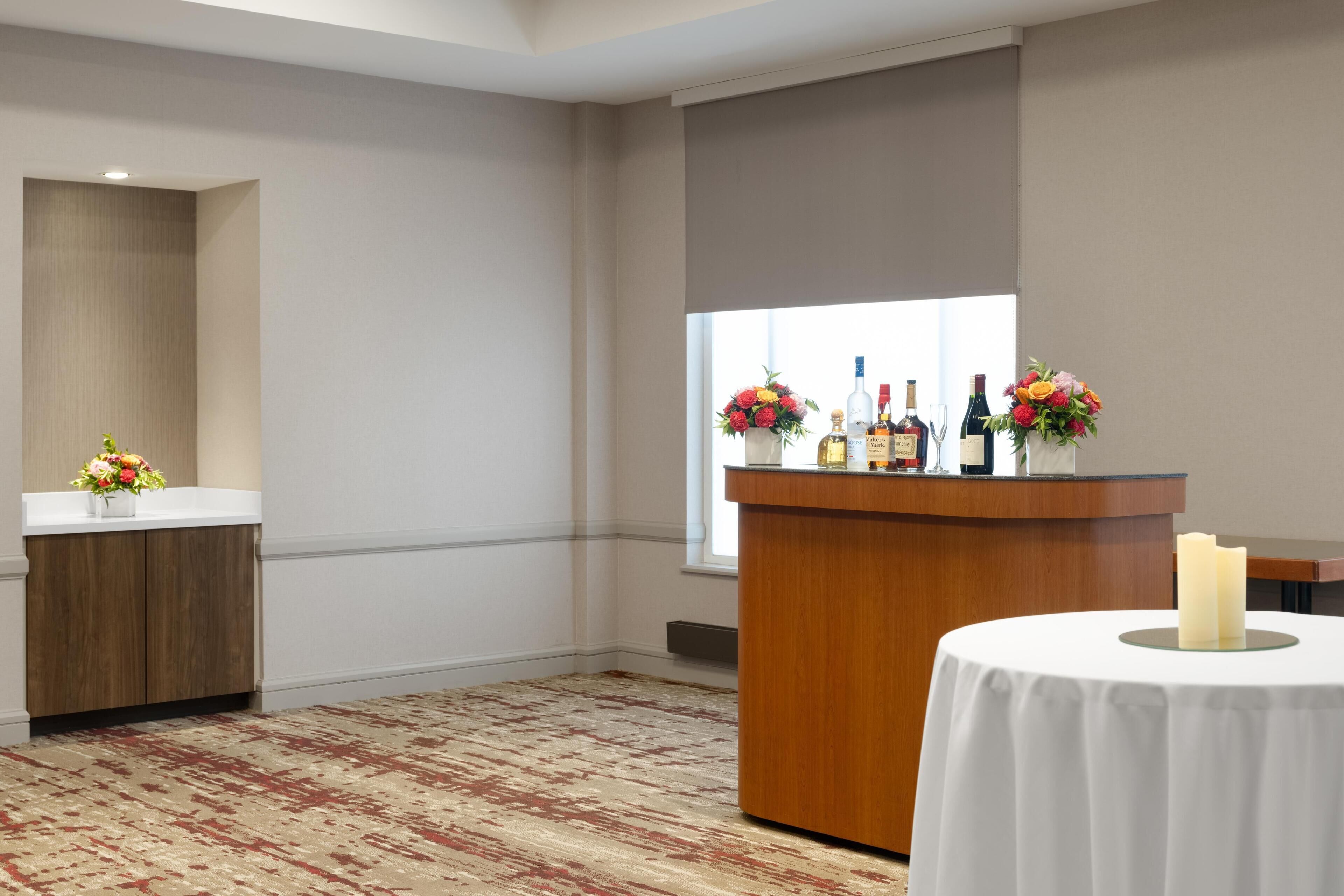 Een hotelkamer met een houten bureau, een witte tafel met een kaars, en een raam met uitzicht.