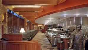 A restaurant with a long counter, seating area, and a kitchen visible in the background. - Hilton Garden Inn Chicago Downtown/Magnificent Mile (Chicago)