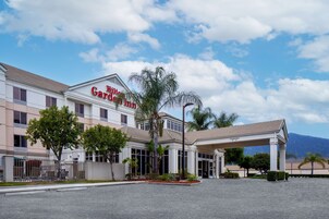 Un hotel con entrada accesible, palmeras y una montaña al fondo.