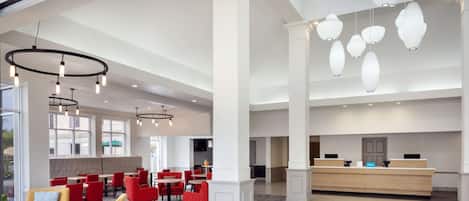 A spacious lobby with a reception desk, seating areas, and modern lighting fixtures.