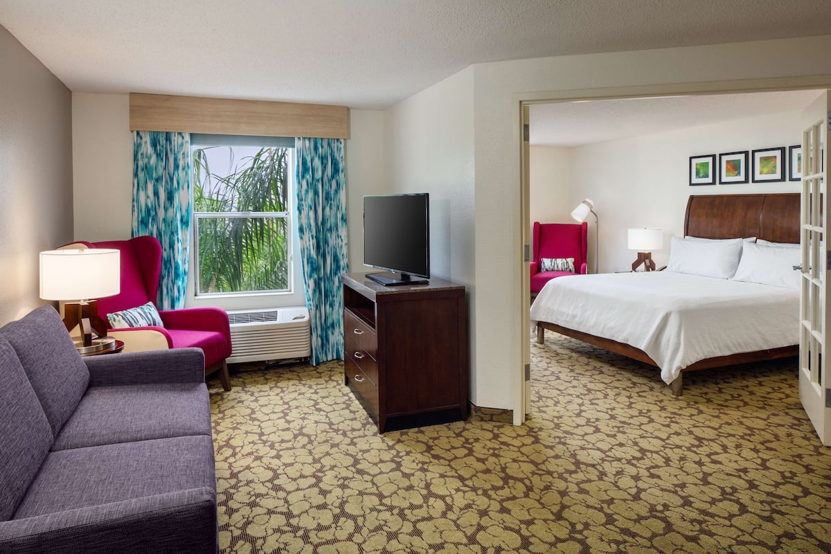 Habitación de hotel con cama, televisión, sofá y escritorio.