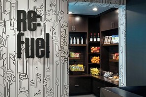 A modern kitchenette with a 'Re-fuel' sign, stocked with beverages, snacks, and fresh produce. - Aloft by Marriott Mountain View (Mountain View)