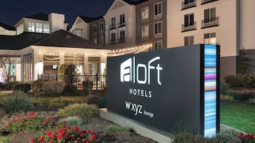 A hotel sign with the name 'aloft hotels' and a lounge area with string lights.