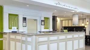Una cocina moderna con una isla central, un mostrador de recepción y un cartel que indica el camino hacia el jardín.
