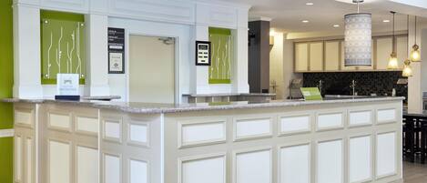 A modern kitchen with a central island, a check-in counter, and a sign indicating a garden's path.