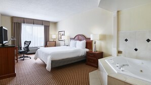 Una habitación de hotel con cama, escritorio, silla, lámparas y bañera.