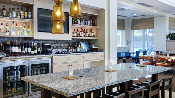Una cocina moderna con barra, encimeras de granito y una isla grande con taburetes de bar.