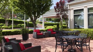 Un área de patio al aire libre con muebles de mimbre, una mesa y sillas.