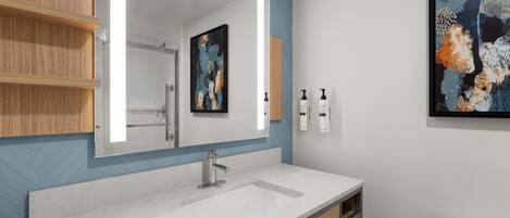 A modern bathroom with a large mirror, a sink, and a toilet.