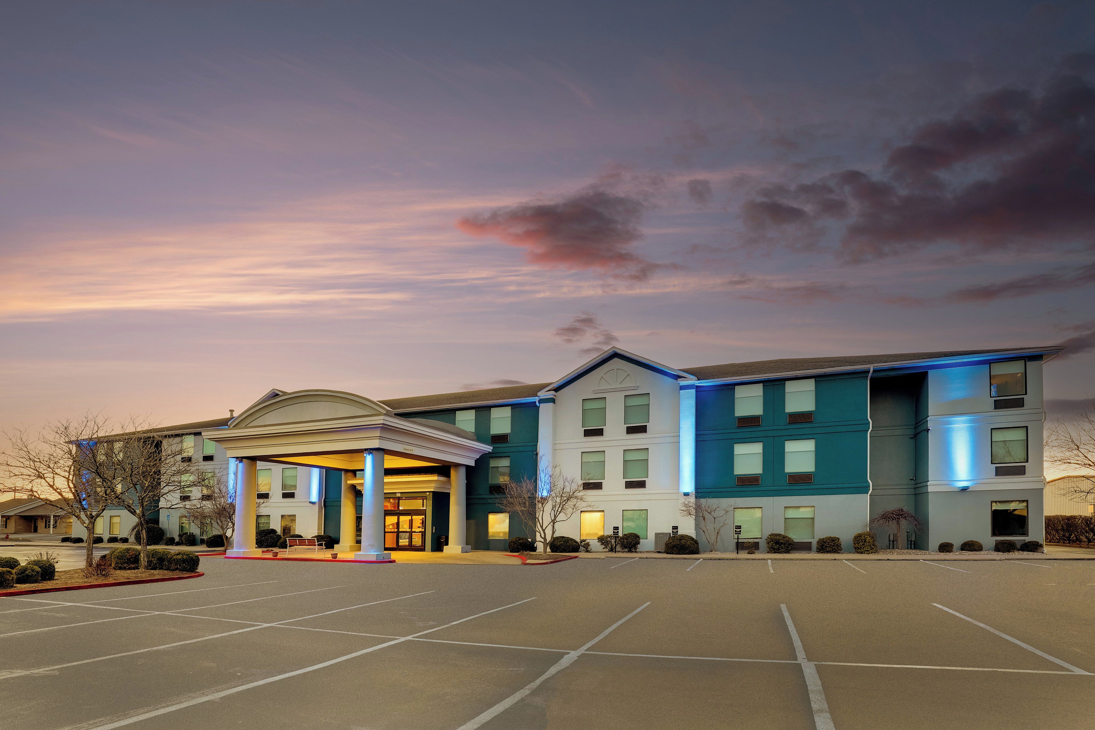 A hotel with a central entrance, multiple floors, and a parking lot.