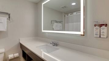 Un baño moderno con un lavamanos blanco, un espejo y una cortina de ducha.
