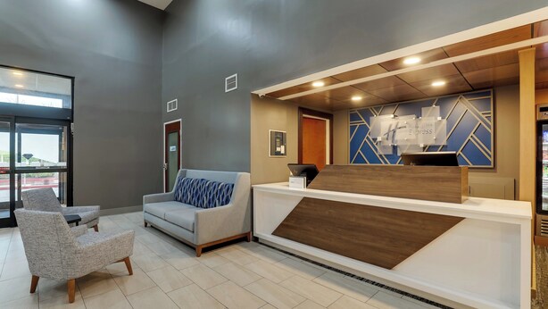A reception area with a modern design, including a reception desk, a sofa, and a chair. - Holiday Inn Express Nicholasville by IHG (Nicholasville)