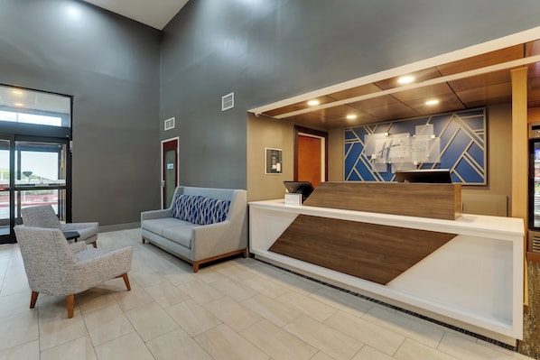 A reception area with a modern design, including a reception desk, a sofa, and a chair. - Holiday Inn Express Nicholasville by IHG (Nicholasville)