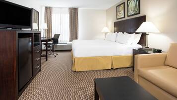 Een hotelkamer met een bed, een televisie, een bureau, een stoel en een bank.