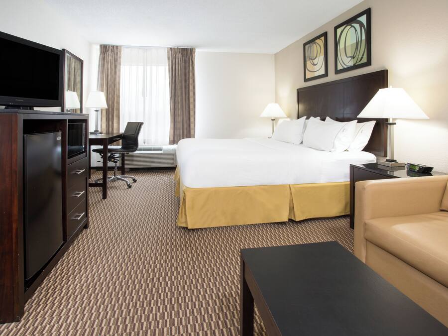Een hotelkamer met een bed, een televisie, een bureau, een stoel en een bank.