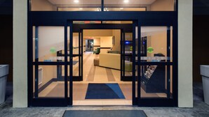 A hotel entrance with a glass door, a reception area, and a staircase leading to the upper floor. - Holiday Inn Express Nicholasville by IHG (Nicholasville)