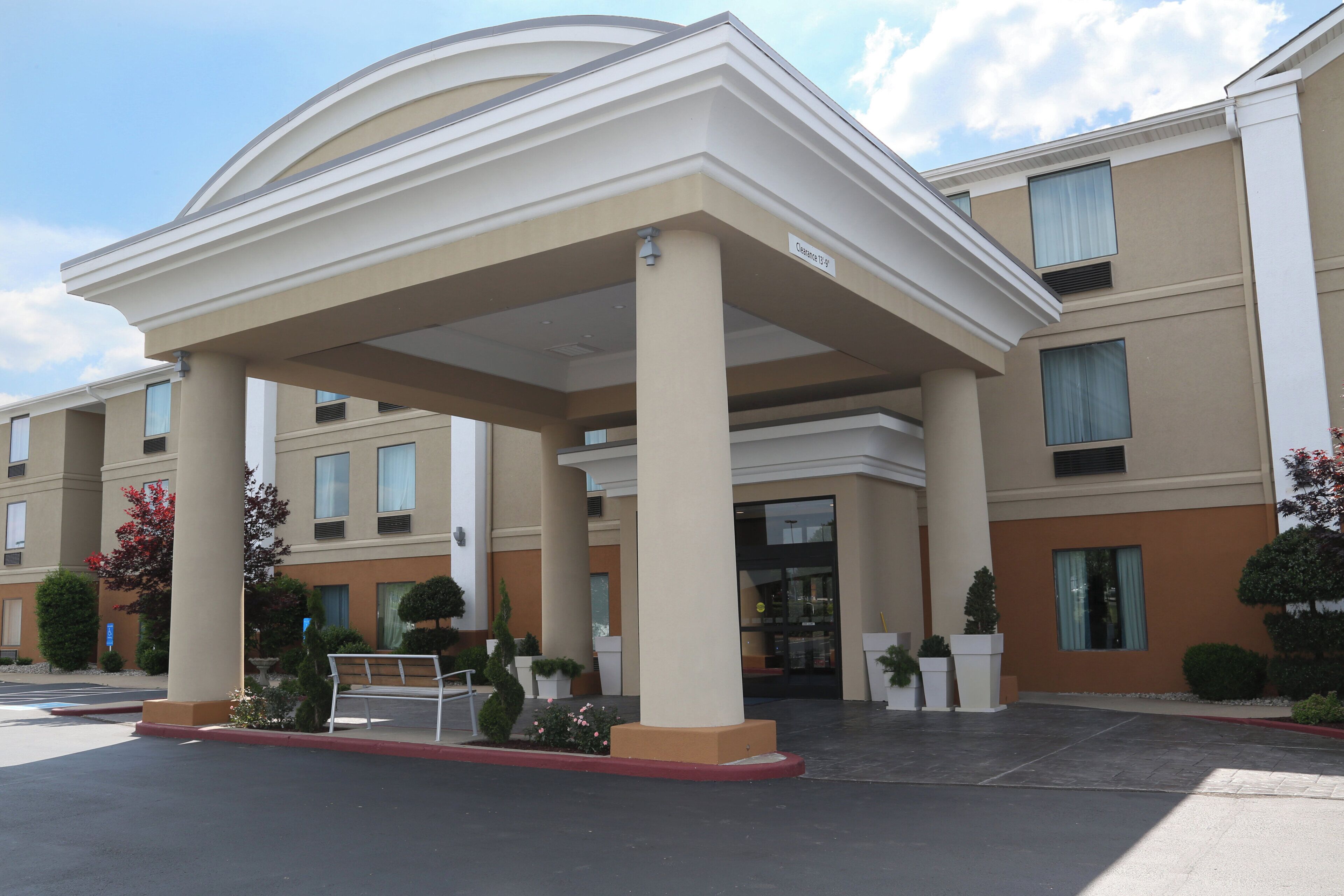 A hotel entrance with a covered walkway, multiple windows, and a clear sky.
