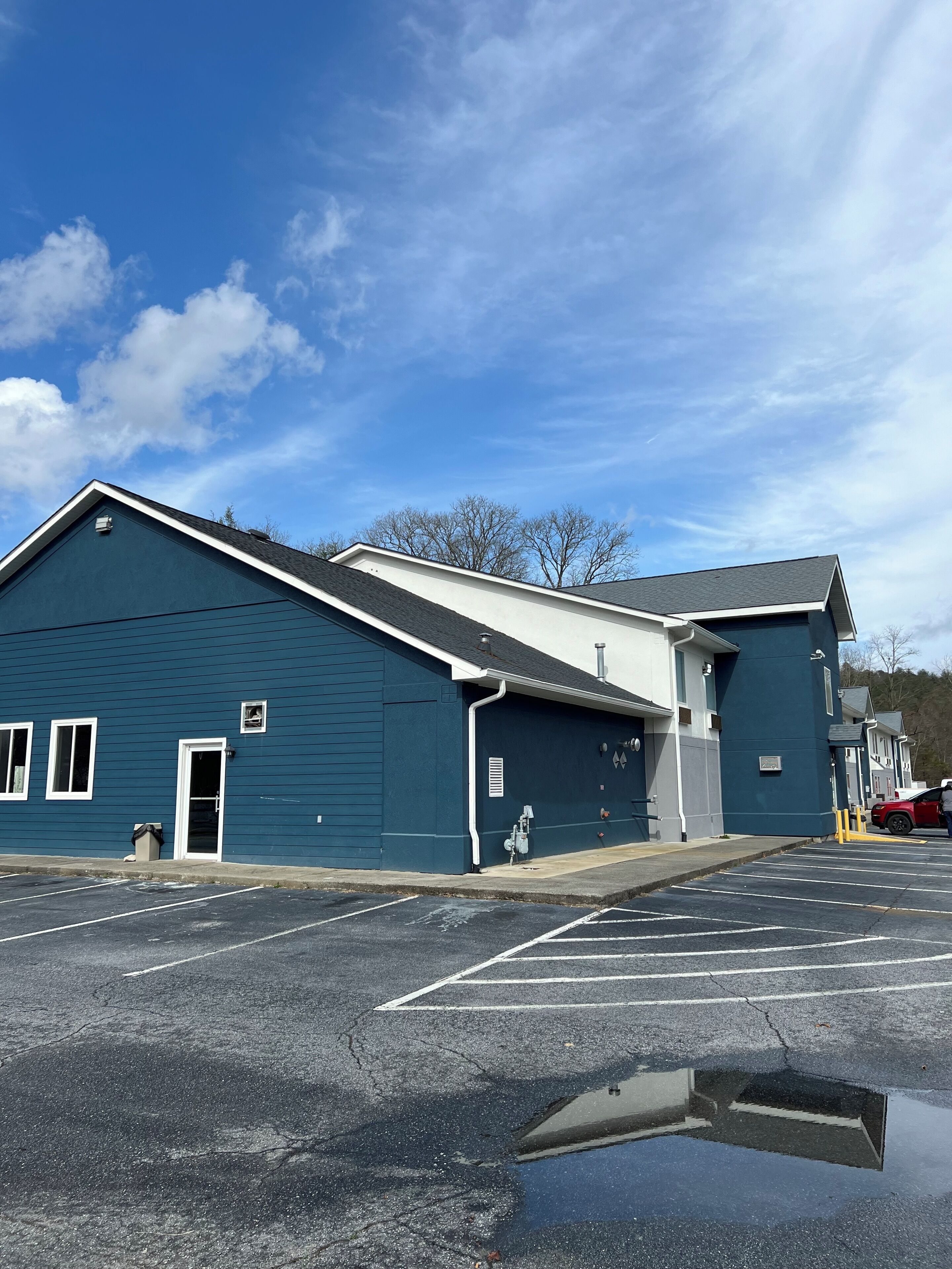 A large blue building with a flat roof, a door, and a small window.