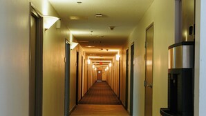 A long, narrow hotel corridor with wooden flooring, doors on both sides, and a water dispenser on the right. - Clarion Pointe-Dillard near Blue Ridge Mountains (Dillard)