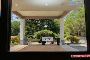 An entrance with an automatic door, a bench, and a sign indicating an emergency push to open.
