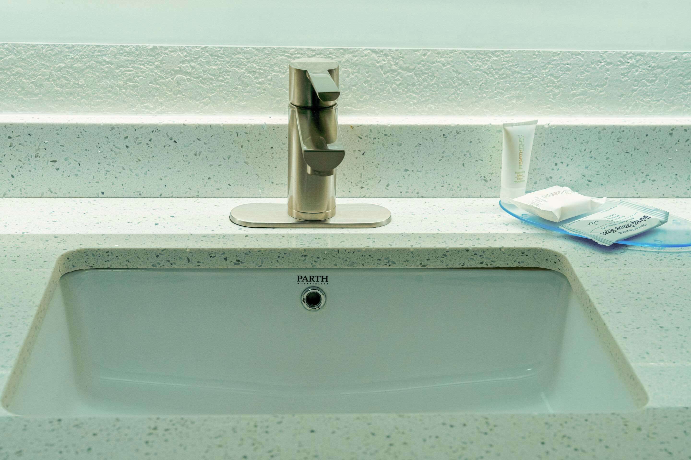 Un lavabo de salle de bain doté d’un robinet moderne, d’un distributeur de savon et d’une petite poubelle.