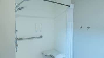 A bathroom with a shower, grab bars, a toilet, and a towel rack.