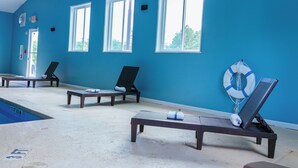 A pool area with lounge chairs and a lifebuoy against a blue wall. - Clarion Pointe-Dillard near Blue Ridge Mountains (Dillard)
