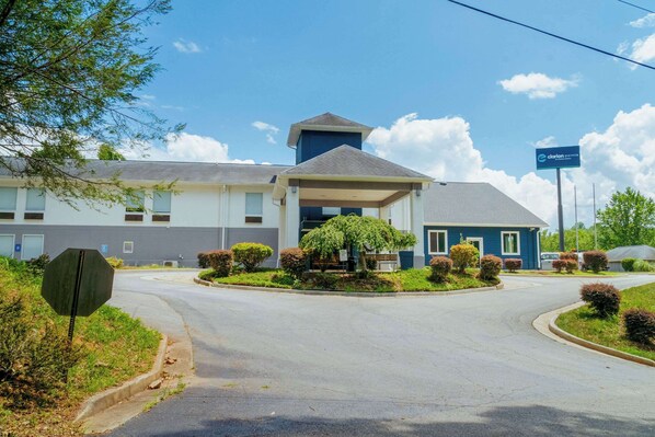 A hotel with a central entrance, a covered waiting area, and a parking lot. - Clarion Pointe-Dillard near Blue Ridge Mountains (Dillard)