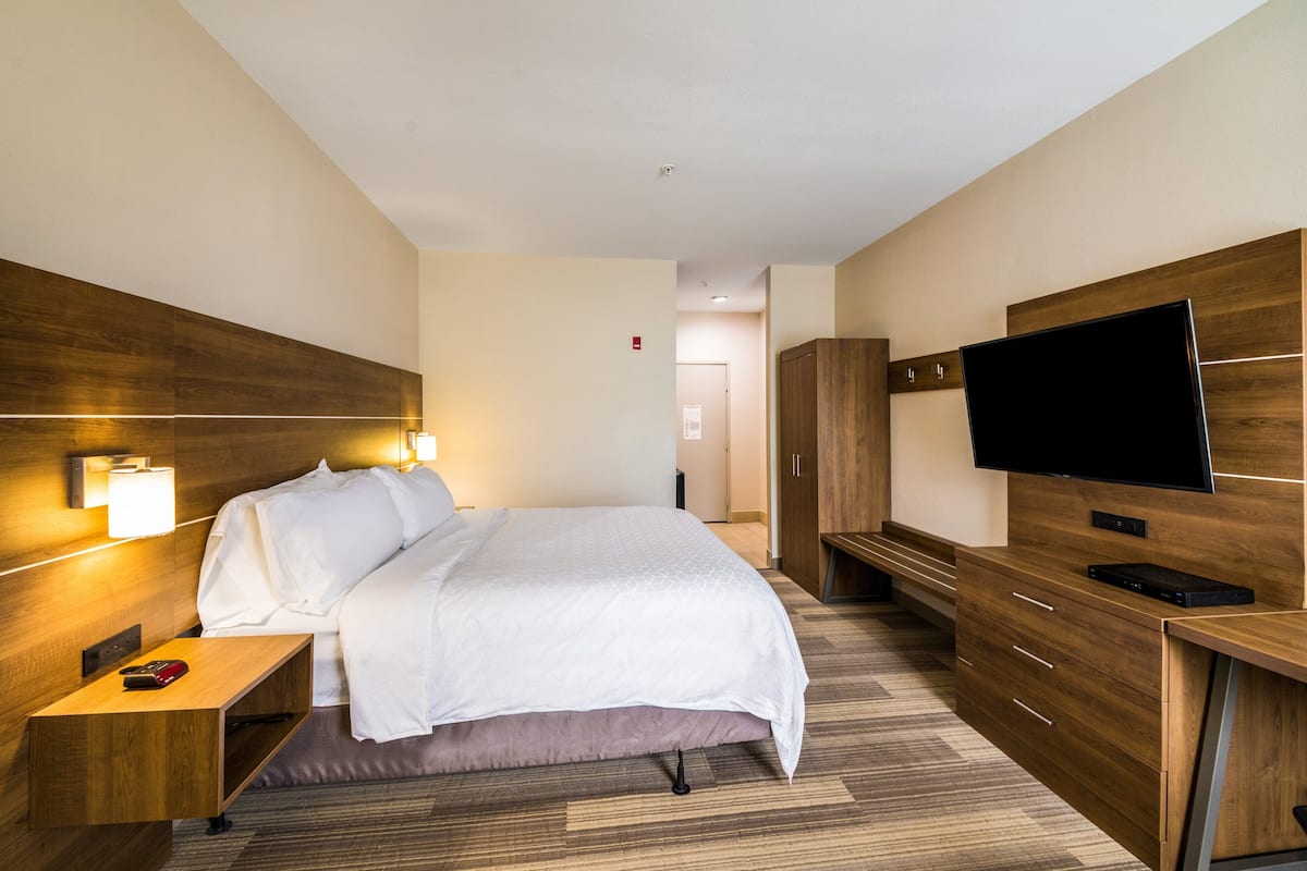 Une chambre d’hôtel comprenant un lit, une table de chevet, une télévision, une armoire et un bureau.