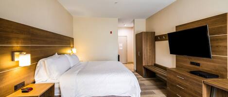 A hotel room with a bed, bedside table, TV, wardrobe, and a desk.