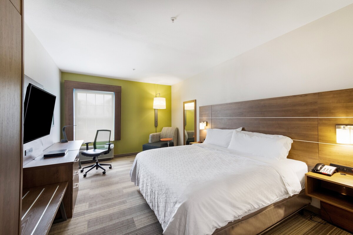 Una camera d'albergo con un letto, una scrivania, una sedia e una televisione.