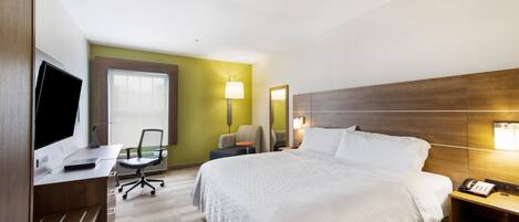 A hotel room with a bed, desk, chair, and a TV.