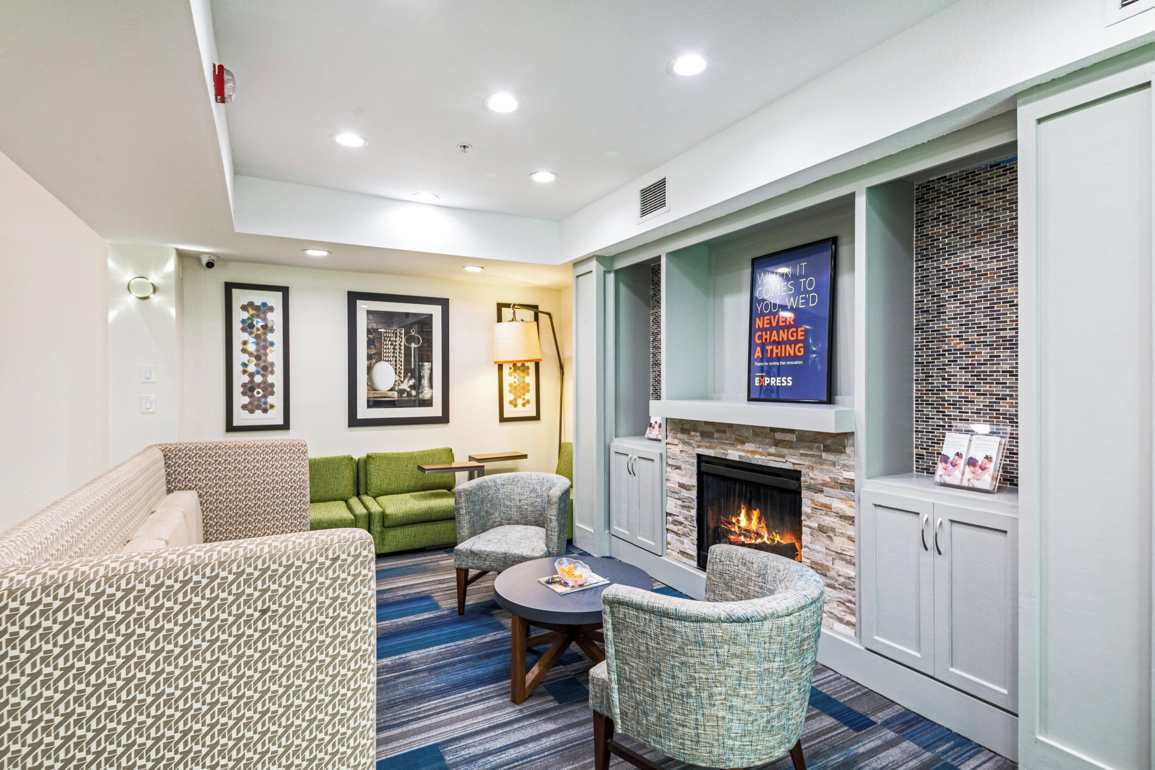 Una sala de estar moderna con chimenea, muebles verdes con estampado y una alfombra azul.