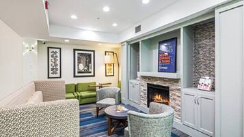 Una sala de estar moderna con chimenea, muebles verdes con estampado y una alfombra azul.