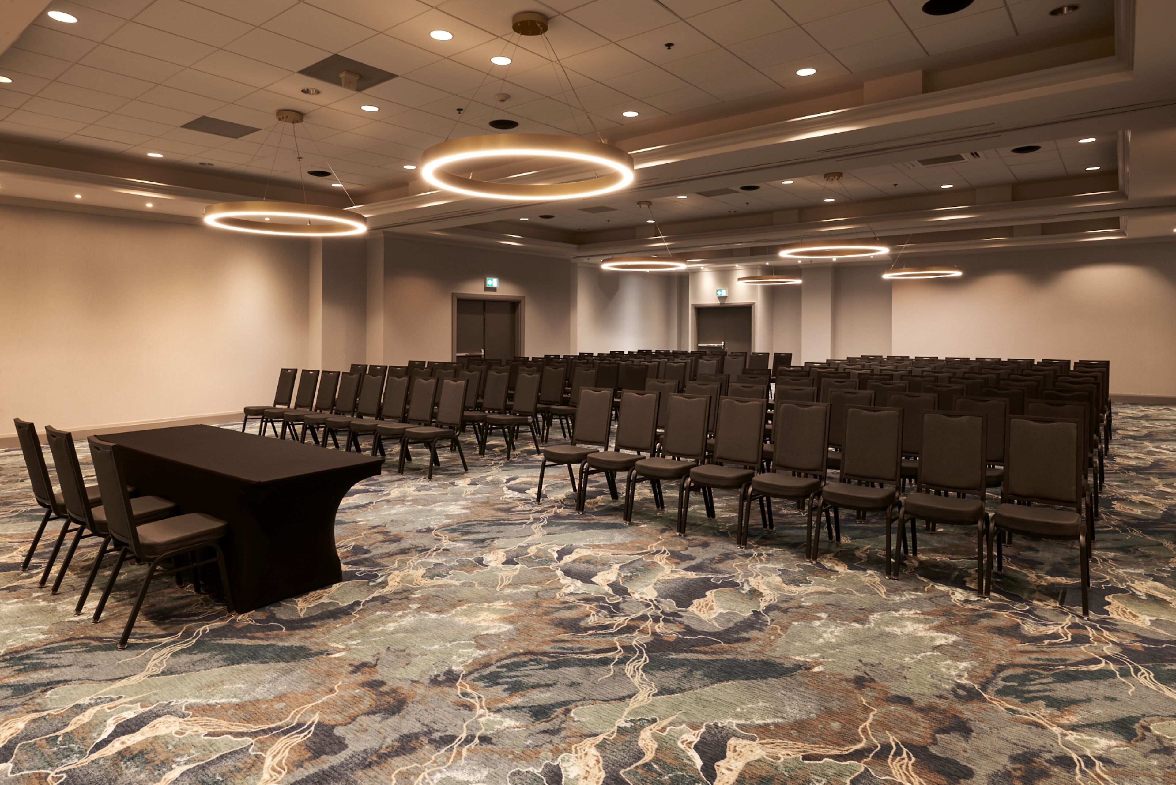 A conference room with a long table and chairs, a patterned carpet, and circular ceiling lights.