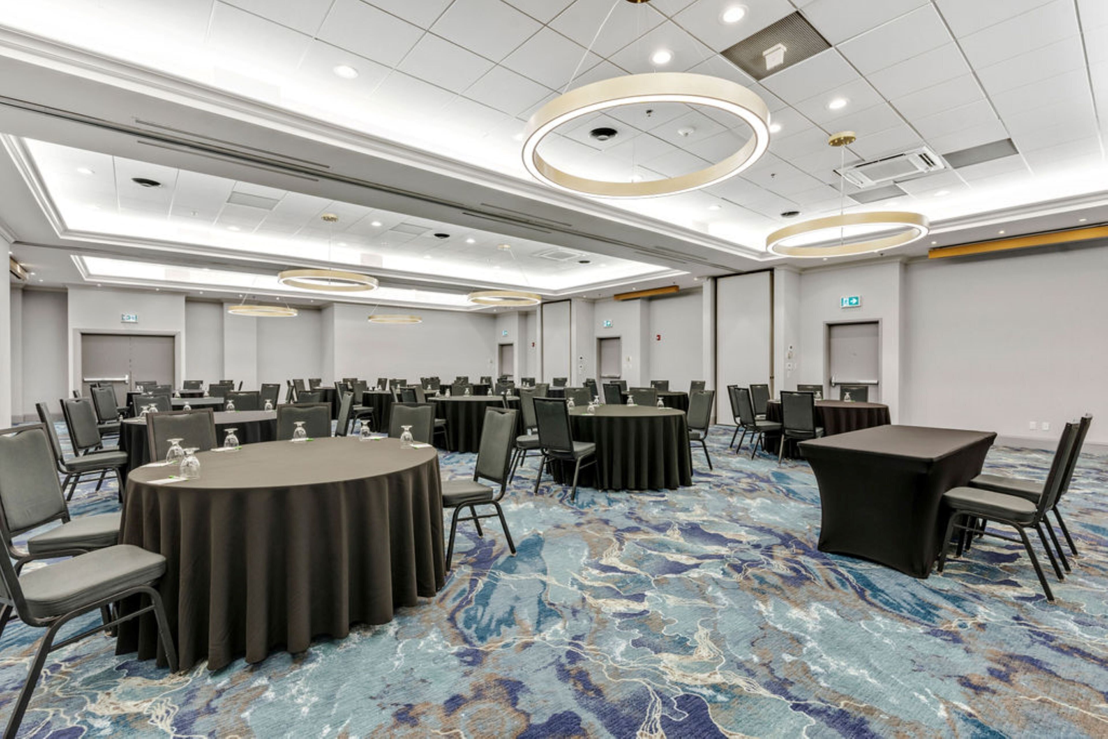 A conference room with round tables, chairs, and a patterned carpet.