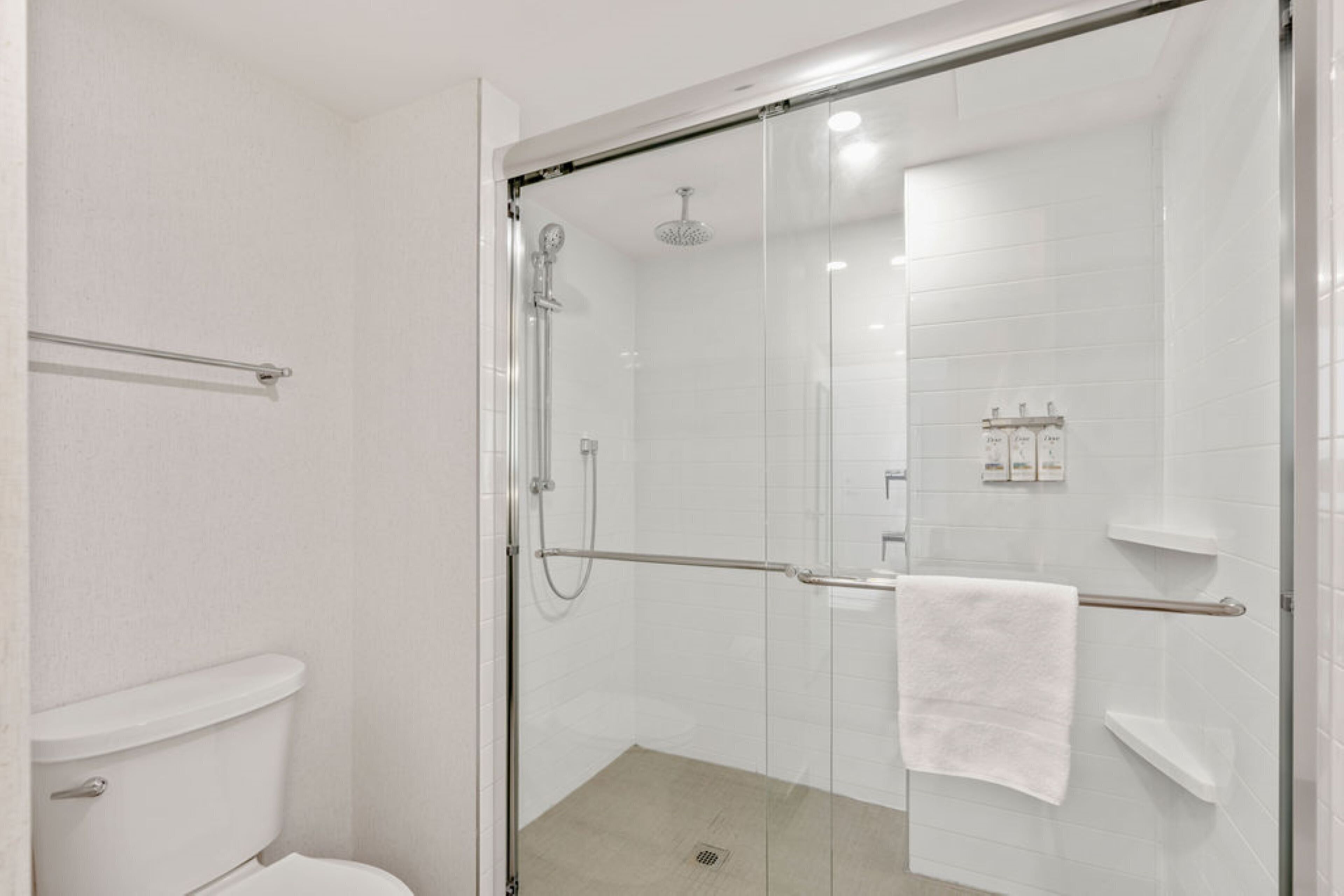 Un baño moderno con ducha envuelta en vidrio, inodoro blanco y un perchero para toallas.