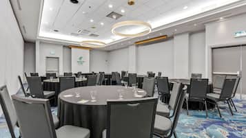 A conference room with round tables, chairs, and a blue carpeted floor.